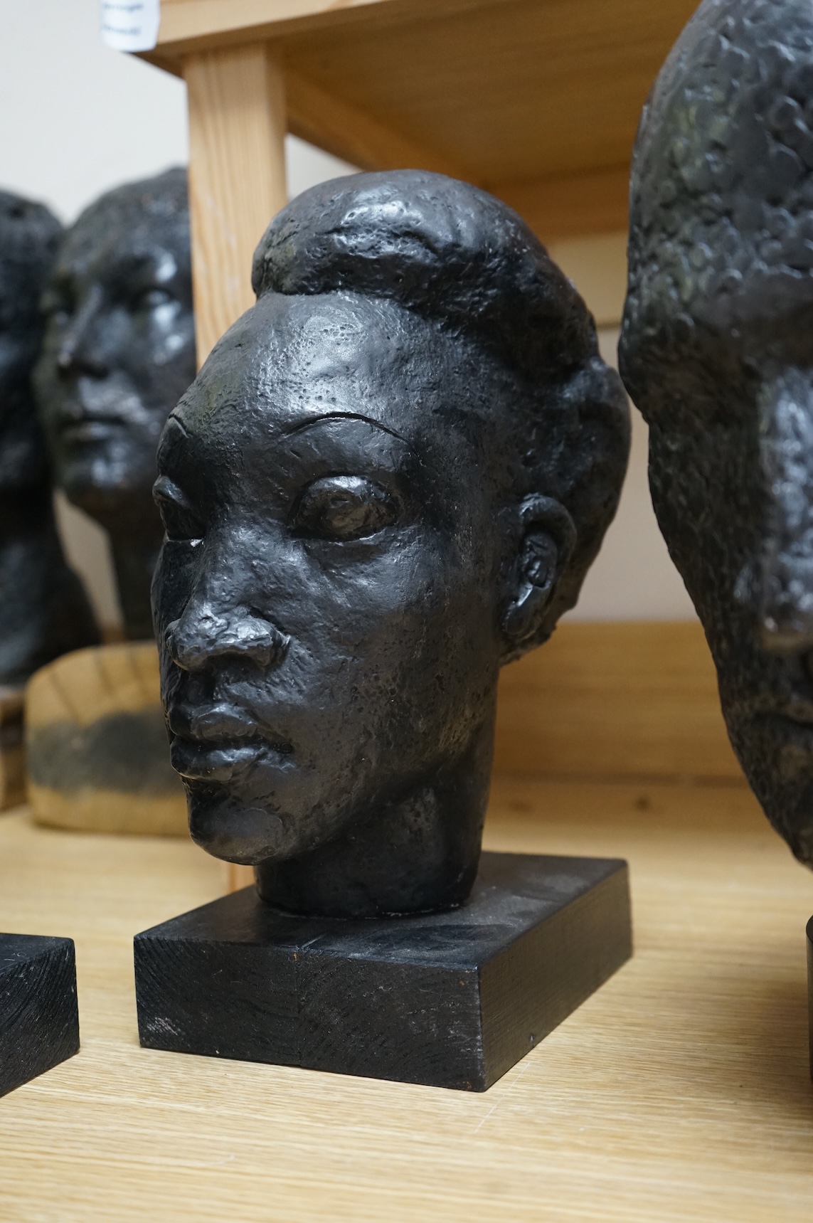 Six black painted composition heads, by Hazel Armour, tallest 49cm